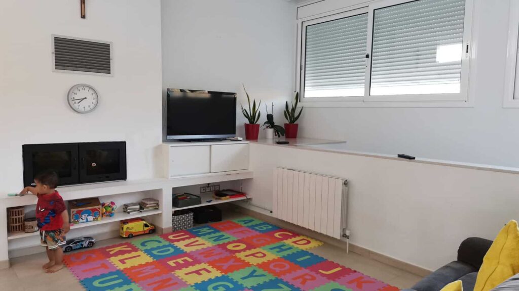 a photo of a clean and organized living room with a toddler playing to signify the importance of cleaning the house before the start of a family staycation.