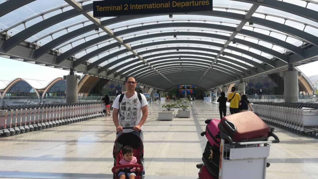 A photo of a father with a small boy on a stroller in an airport ready for their first long flight.