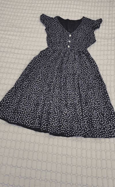 a photo of a black and white summer dress with 3 buttons on the bust area.