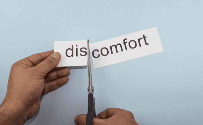 a photo of a paper with the word discomfort and a scissors cutting the word "dis" to signify the comfort that one gets as one of the benefits of dressing modestly.
