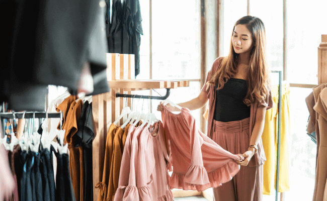 a mom looking and touching a peach blouse as a sign of choosing clothing wisely - one of the modest dressing tips for moms