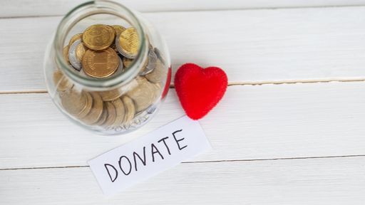 photo of a donation jar with coins and a heart beside the jar and a paper with the word donate - to signify making a donation as one of the lenten activities for families