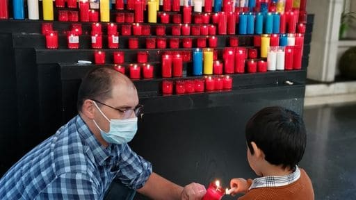 photo of a father and his son lighting candle to offer to the altar on their pilgrimage - another family activity during Lent