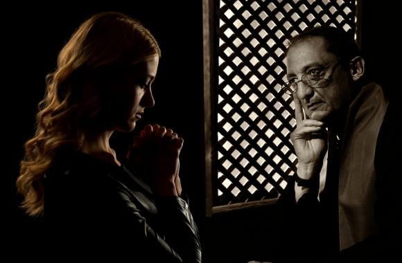 photo of a woman in a confessional with a priest to signify going to confession - one of the Catholic staycation ideas for families