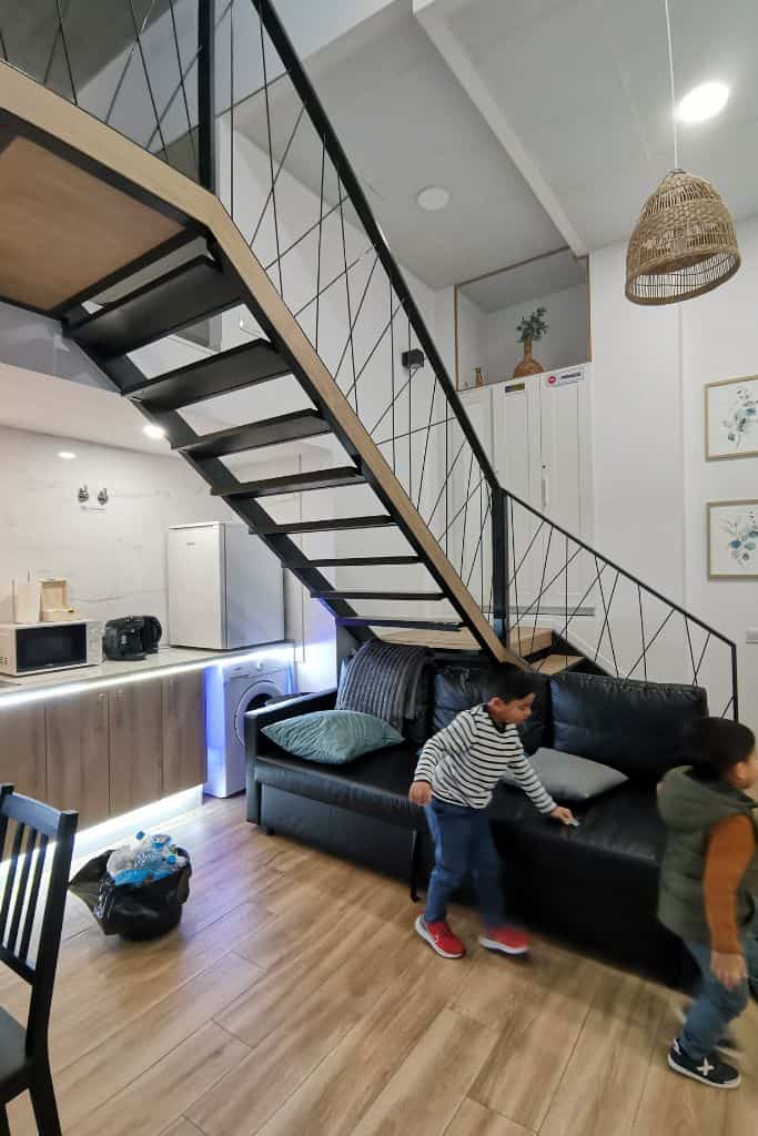 photo of the stairs and the sofa with kids playing in the living room showing the minimalist and modern aesthetic of Grandera apart's - Carbonell 1