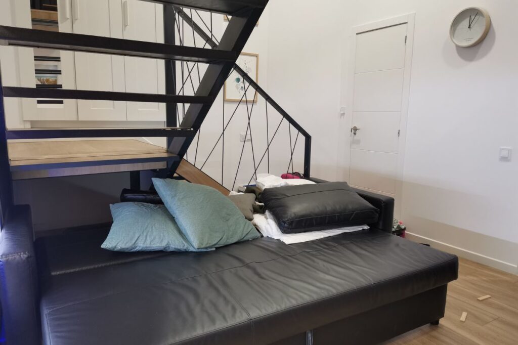 photo of a sofa bed under the stairs.
